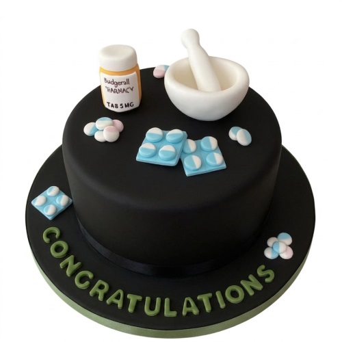 Black round cake with pharmacy themed decorations including a pill bottle, mortar and pestle, and blister packs. 'Congratulations' written on the base.