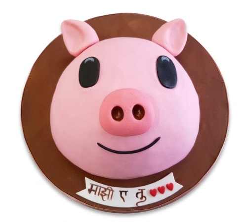Round pink pig face birthday cake with black eyes, pink snout, and a white banner with red hearts.