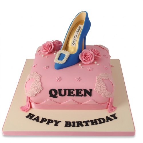 Pink square birthday cake with a blue high heel shoe, pink roses, pearls, and lace details, with a personalised message.