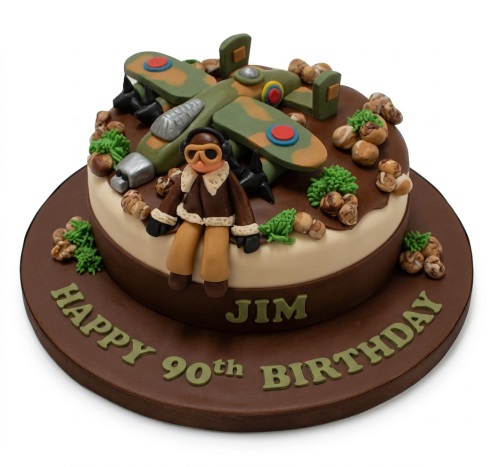 Two-tier brown and cream cake with green camouflage aeroplane, pilot figure, and custom message.