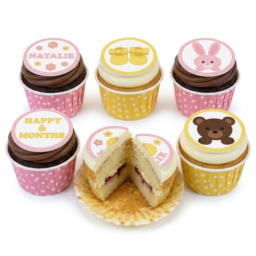 Baby shower cupcakes with pink and yellow polka dot wrappers, featuring baby booties, bunny, teddy bear, and custom message toppers.