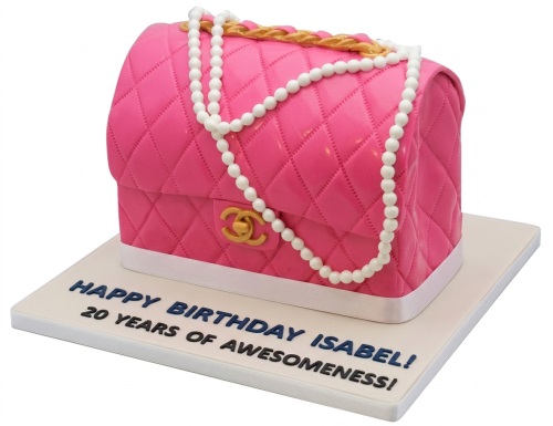 Pink quilted handbag cake with gold chain and pearl decorations on a white board.