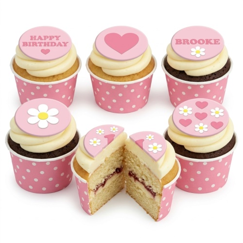 Pink cupcakes with white icing, decorated with pink floral and heart toppers, in polka dot wrappers.