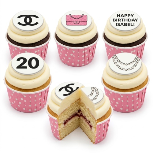 Chanel inspired cupcakes with pink polka dot cases, white frosting, and toppers featuring a Chanel logo, pink handbag, pearl necklace, a custom age, and a personalised birthday message.