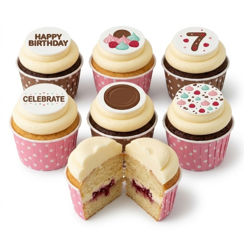 A selection of vanilla and chocolate cupcakes with cream frosting, topped with edible discs featuring 'Happy Birthday', 'Celebrate', a number '7', meringues, raspberries, and a chocolate disc, in pink and brown polka dot wrappers.