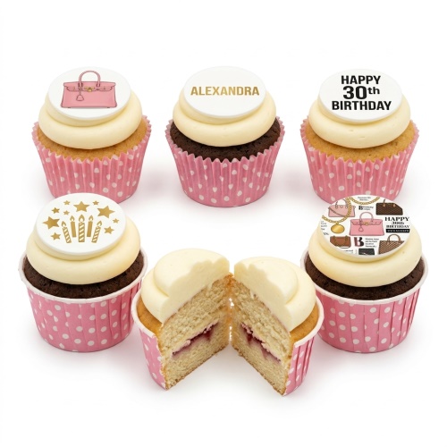 Cupcakes with white frosting, pink wrappers, and edible designer handbag, stars, candles, and custom name/age toppers.