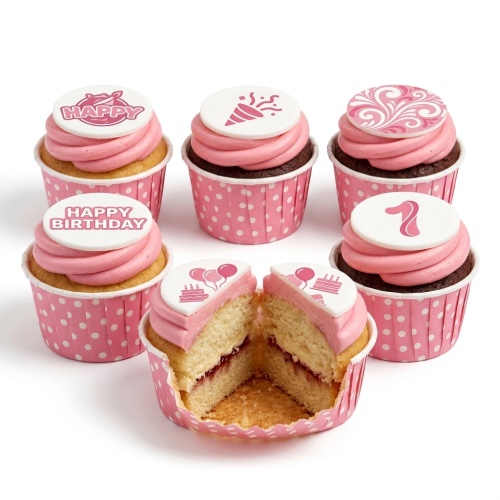 Pink cupcakes with polka dot wrappers and various birthday celebration toppers.