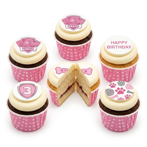 Set of Paw Patrol themed cupcakes in pink polka dot cases, with white frosting and various pink Paw Patrol edible toppers including logo, paw prints, and a number shield.