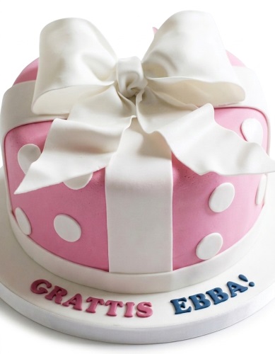 Pink gift box cake with white ribbon and bow, decorated with white polka dots.