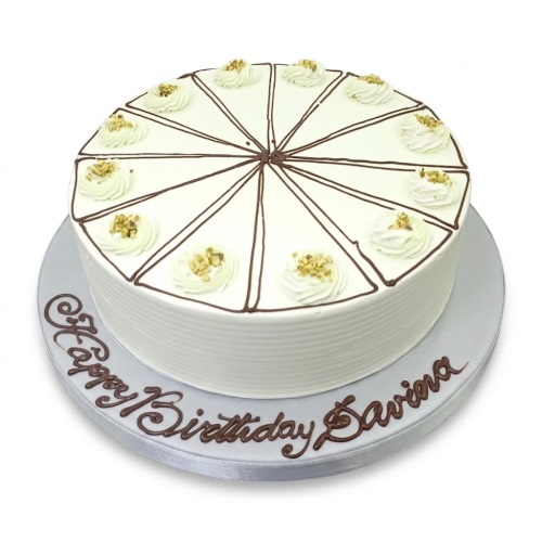 Round cream birthday cake with chocolate lines, whipped cream swirls, and nuts, with a personalised message.