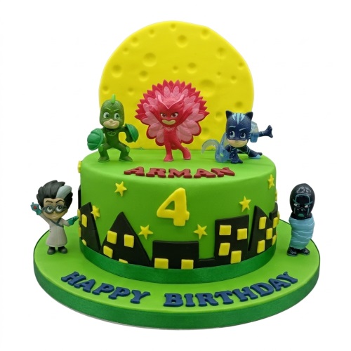Green PJ Masks birthday cake with character figurines, city skyline, moon, and custom age.