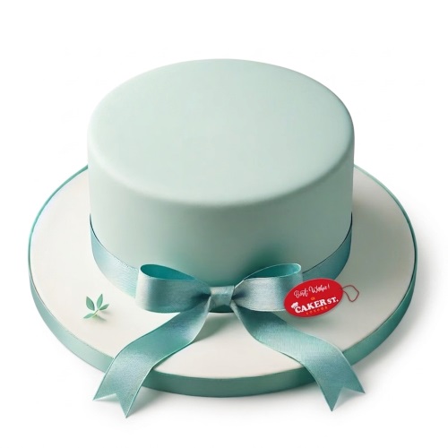Elegant pastel blue single-tier birthday cake with a satin ribbon bow and small green leaf decoration.