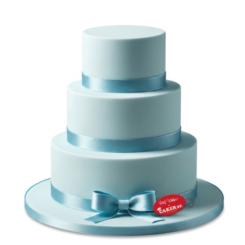 Three-tiered light blue cake with satin ribbons and a bow, suitable for a baby shower.