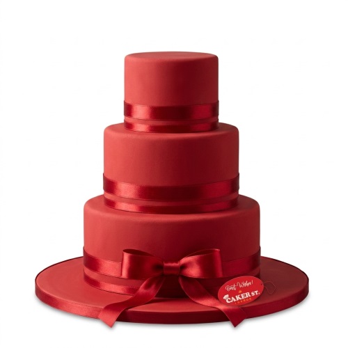 Three-tiered red birthday cake with satin red ribbons and a bow.