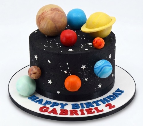 Black space themed birthday cake with colourful edible planets and white stars, with custom message.