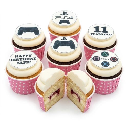 PlayStation themed birthday cupcakes with controllers, PS4 logo, and PlayStation button symbols on white frosting in pink polka dot cases.