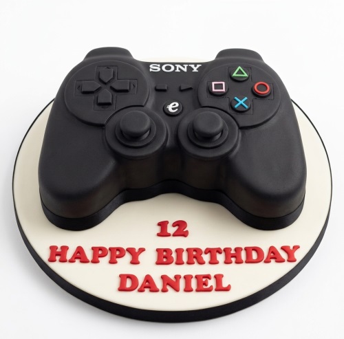 Black PlayStation controller shaped birthday cake with custom age and happy birthday message.