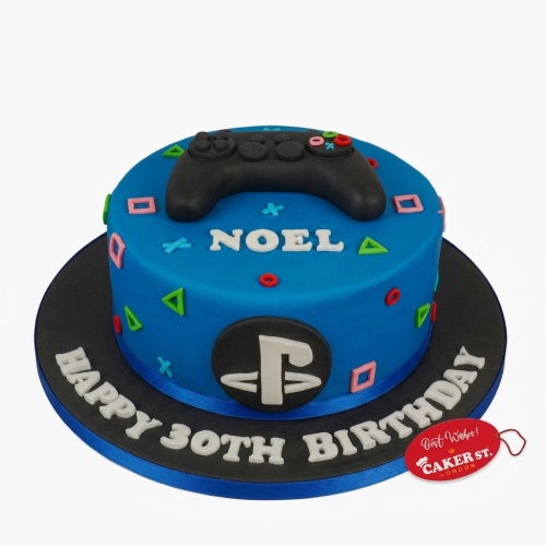 Blue gaming birthday cake with a black PlayStation controller and colourful button symbols.