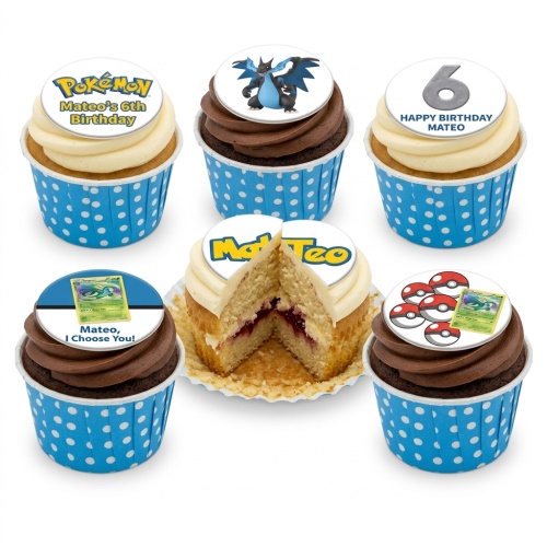 Pokemon themed cupcakes with various toppers including the Pokemon logo, Charizard, Pokeballs, and a Dragonair trading card, in blue polka dot wrappers.