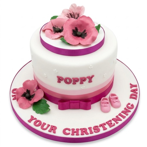 White two-tier christening cake with pink poppy flowers, baby shoes, and custom name.