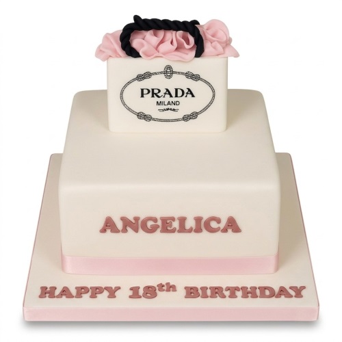 Two-tier white cake with a Prada shopping bag topper, pink ribbon, and custom message.