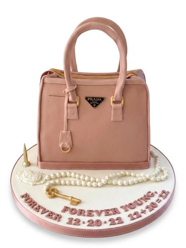 Pink designer handbag shaped birthday cake with a Prada logo, pearl beads, and a gold key.