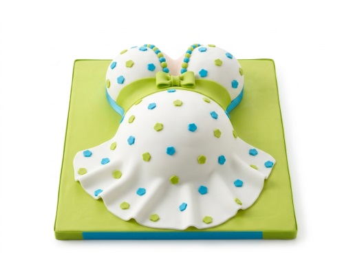 White pregnant belly cake with green ribbon, blue and green polka dots on a lime green board.