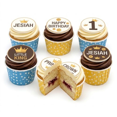 Assortment of crown-themed birthday cupcakes with white and brown frosting, blue and yellow polka dot wrappers.