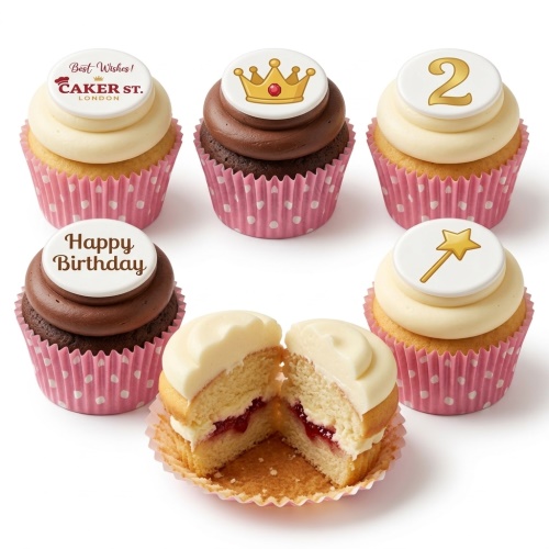 Vanilla and chocolate cupcakes with white and brown frosting, topped with edible crown, magic wand, custom age '2', and 'Happy Birthday' toppers. Pink polka dot wrappers.