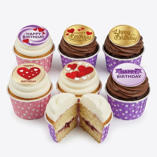 Assortment of Happy Birthday cupcakes with heart toppers, pink and purple polka dot wrappers.