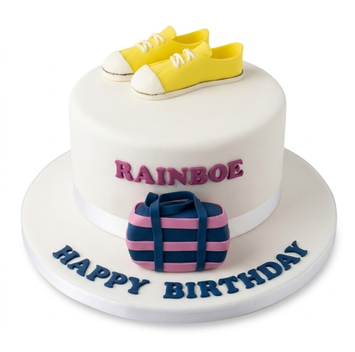 White round birthday cake decorated with yellow trainers and a blue and pink duffel bag, with a custom name and 'Happy Birthday' message.