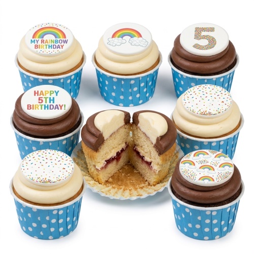 Assortment of rainbow birthday cupcakes with custom age and sprinkle toppers in blue polka dot cases.