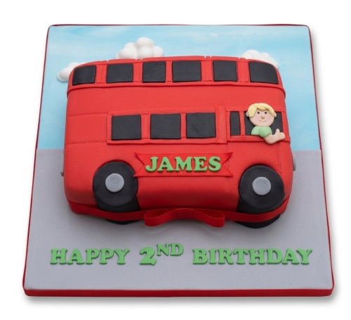 Red double-decker bus birthday cake with a boy figure and custom message on a grey board.