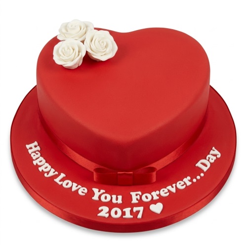 Red heart-shaped anniversary cake with white sugar roses and a red ribbon, on a cake board.