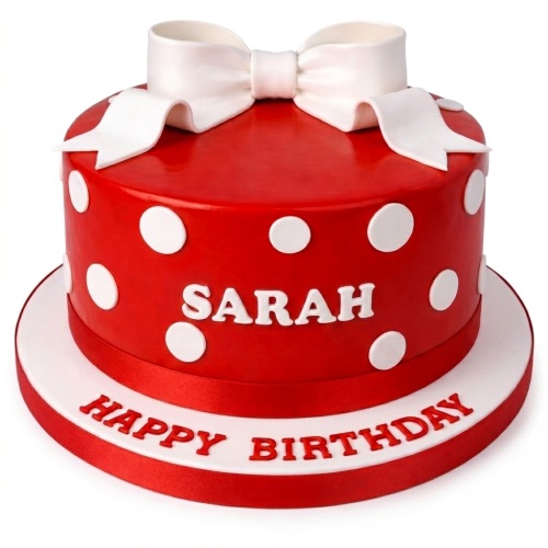 Round red cake with white polka dots and a white bow on top, with a personalised name and happy birthday message.