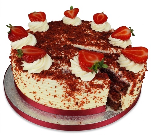 Round red velvet cake with white cream frosting, red velvet crumbs, and fresh strawberry halves.