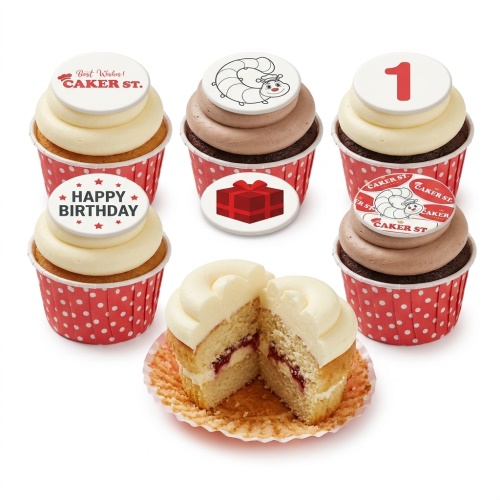 A selection of birthday cupcakes with white and chocolate frosting, red polka dot wrappers, and toppers including a number 1, a caterpillar, and "Happy Birthday".