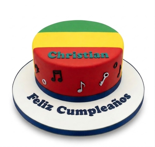 Round single-tier reggae theme birthday cake with green, yellow, red, and blue colours, decorated with musical notes and a key, with a personalised name and message.
