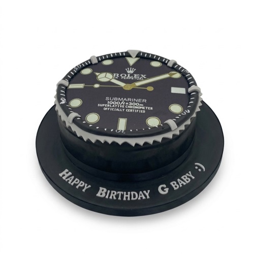 Round black cake designed as a luxury watch face with gold and white details, on a black board with a custom message.