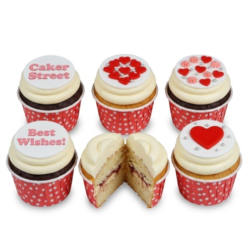 A selection of cupcakes with white frosting, red hearts, and silver pearls, some with chocolate and vanilla sponge.