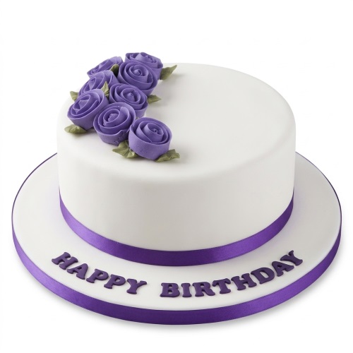 White round birthday cake with piped purple roses, green leaves, and a purple ribbon.