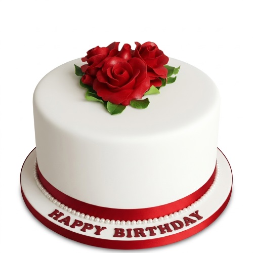 Round white birthday cake with red sugar roses, green leaves, red ribbon, white pearls, and "Happy Birthday" text.