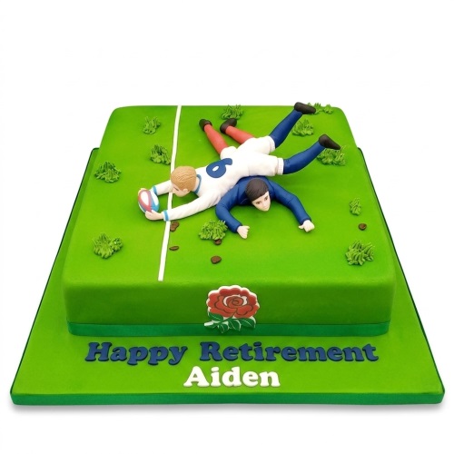Green rugby field cake with two fondant rugby players, a rugby ball, and a red rose emblem.