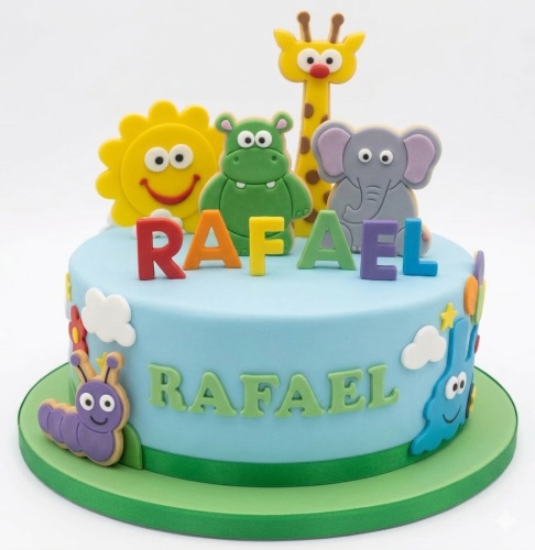 Light blue round cake with cartoon sun, hippo, giraffe, elephant, caterpillar, and colourful letters.