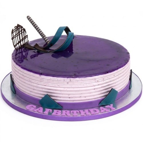 Round purple glaze birthday cake with ribbed sides, chocolate, and teal decorations.