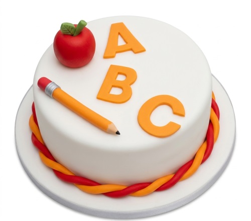 White round cake with orange ABC letters, red apple, and yellow pencil decorations.