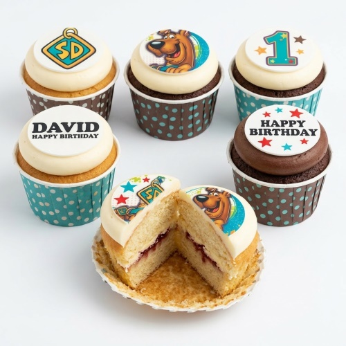 Selection of Scooby-Doo themed birthday cupcakes with character and logo toppers, one with a custom age '1' and another with 'Happy Birthday' message.