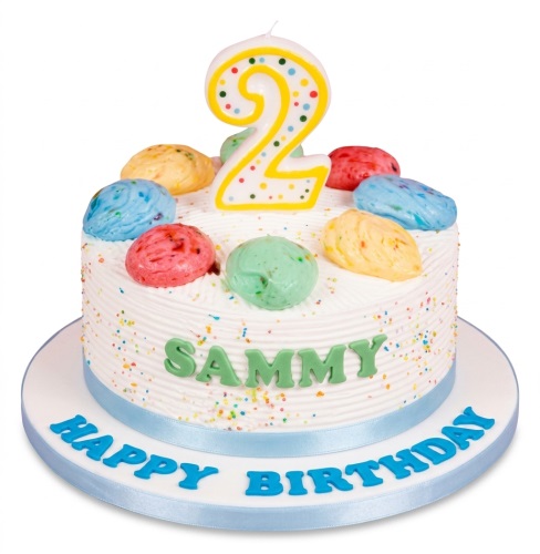 White birthday cake with colourful sprinkles, multi-coloured ice cream scoop decorations, and a number candle.