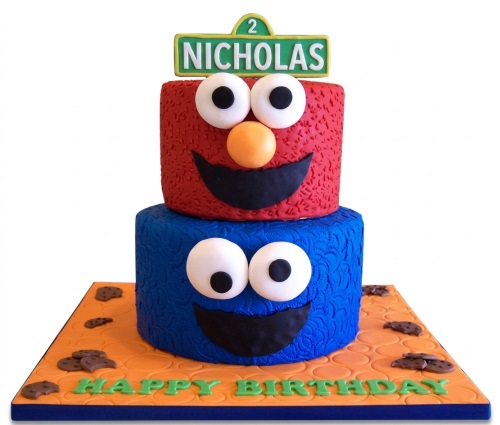 Two-tier Sesame Street birthday cake with Elmo and Cookie Monster, decorated with cookies and a custom age topper.