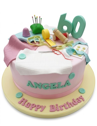 Pink round birthday cake with sewing themed decorations, including a pin cushion, thimble, measuring tape, and thread spools, with a custom age topper.